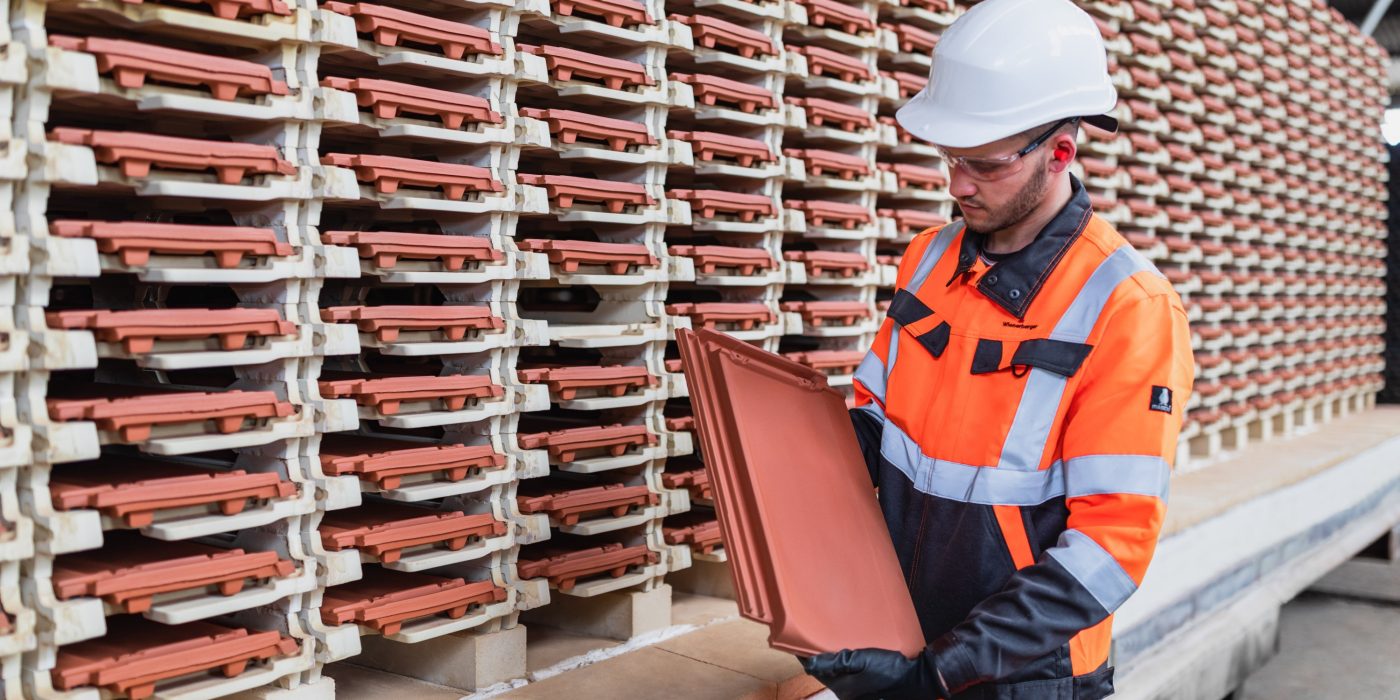 Factory worker checking roof tile quality