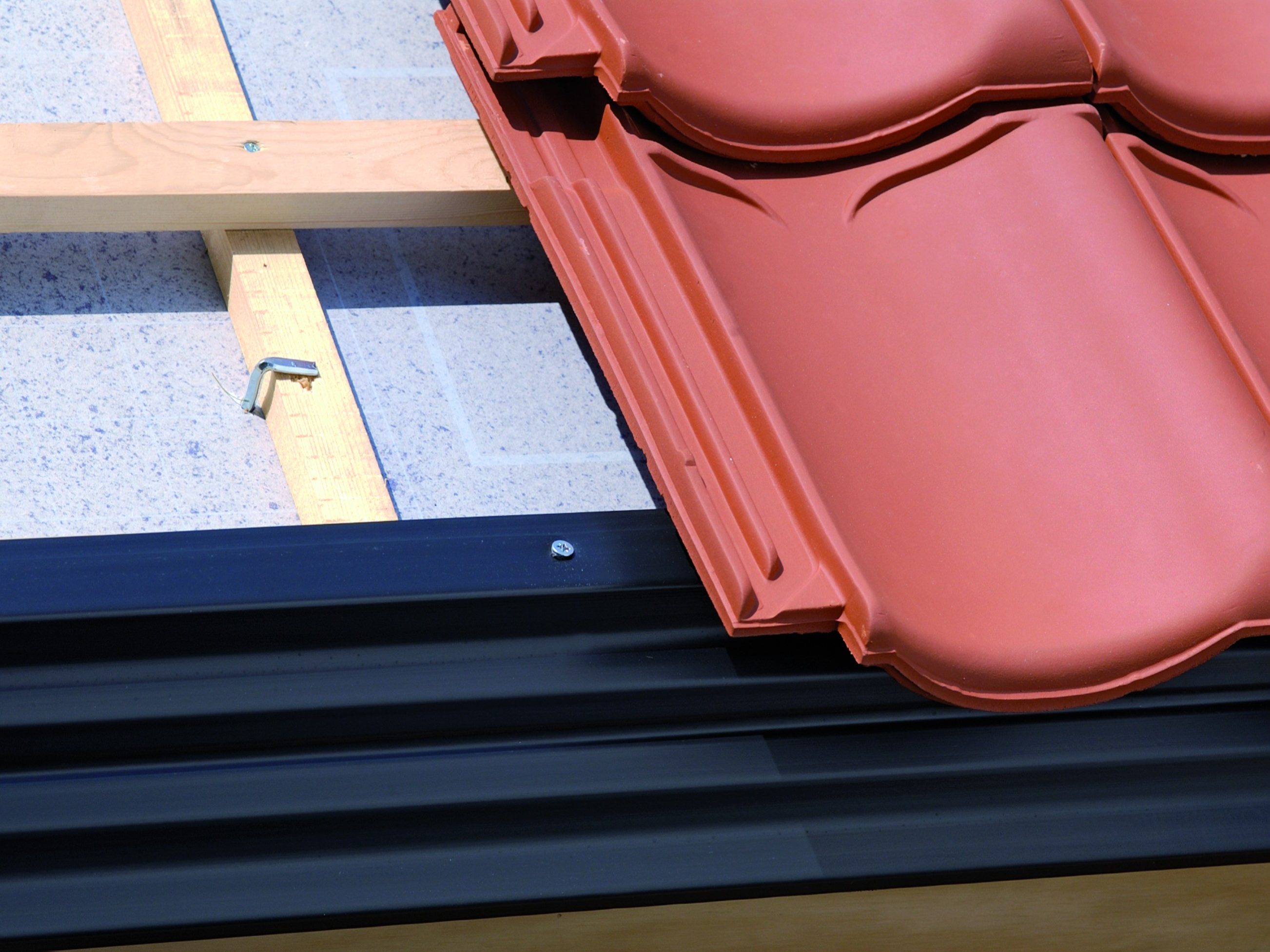 Koramic daktoebehoren: dakvoetafwerking. Dakvoetprofiel. Beschermt het dakbeschot of dakplaat tegen weersinvloeden en opspattend water uit de goot.  Kan alleen of in combinatie met vogelschroot of ventilerende onderlatten worden toegepast. Leverbaar in kunststof (lengte: 1,5 meter; in zwart). Een goede dakvoetconstructie is essentieel voor een goede ventilatie van de dakspouw.  Dakvoetprofielen zorgen voor een mooie afwerking en bescherming tegen regen, wind en stuifsneeuw. Vogels, ratten en muizen worden geweerd met het Koramic combidakvoetprofiel, de vogelschroot of de vogel/muisschroot. Niet keramische kwaliteitsproducten voor een technische en esthetische afwerking. Regendicht en ventilatie mogelijk. Technisch en esthetisch dakafwerking bij aansluitdetails, snijlijnen en ventilatieopeningen.