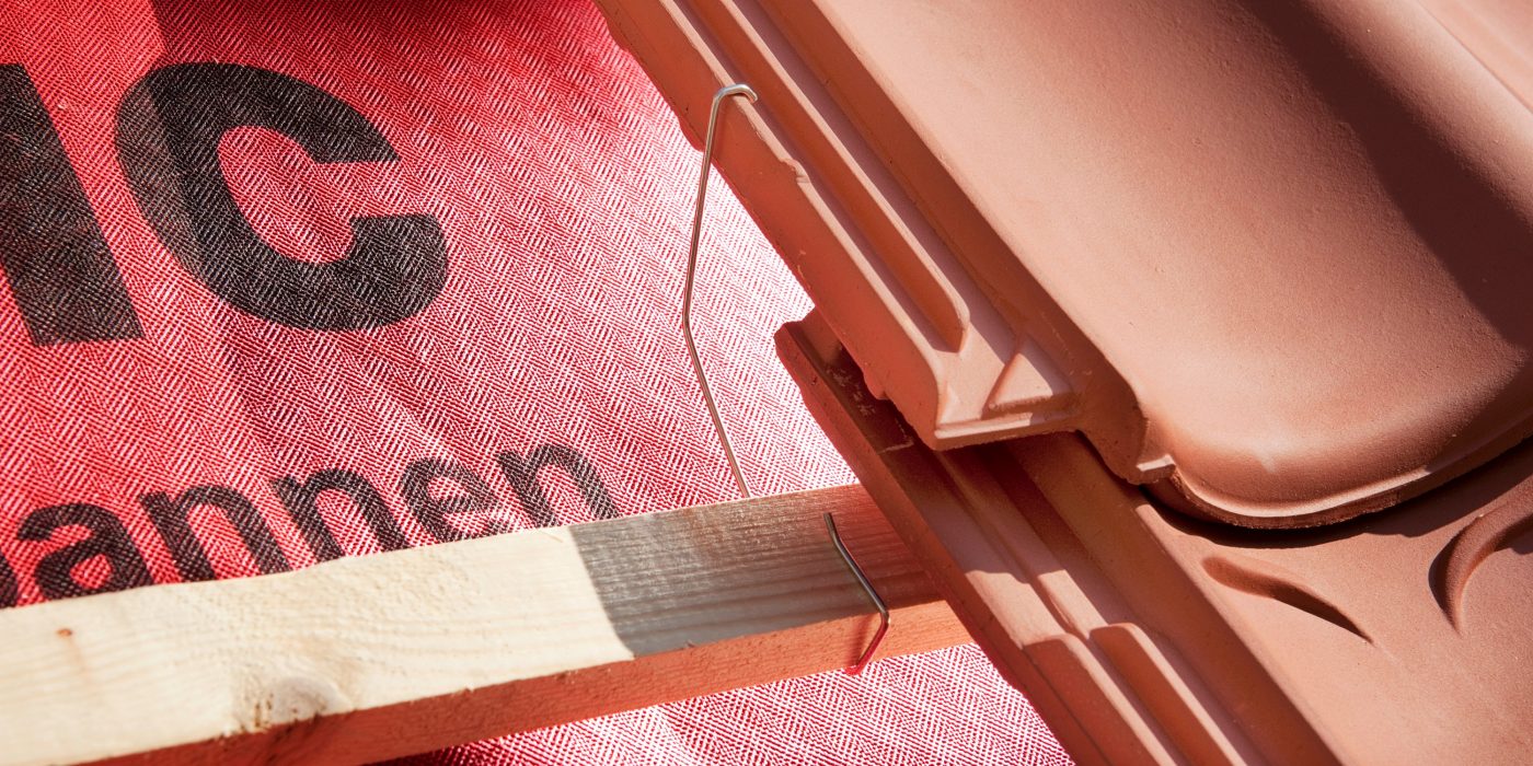 Toepassing detail panhaak. Koramic dakpannen verankeren. Roestvast staal. Duurzaamheidseis binnen het Bouwbesluit: duurzaamheid van de panhaak minimaal 50 jaar.