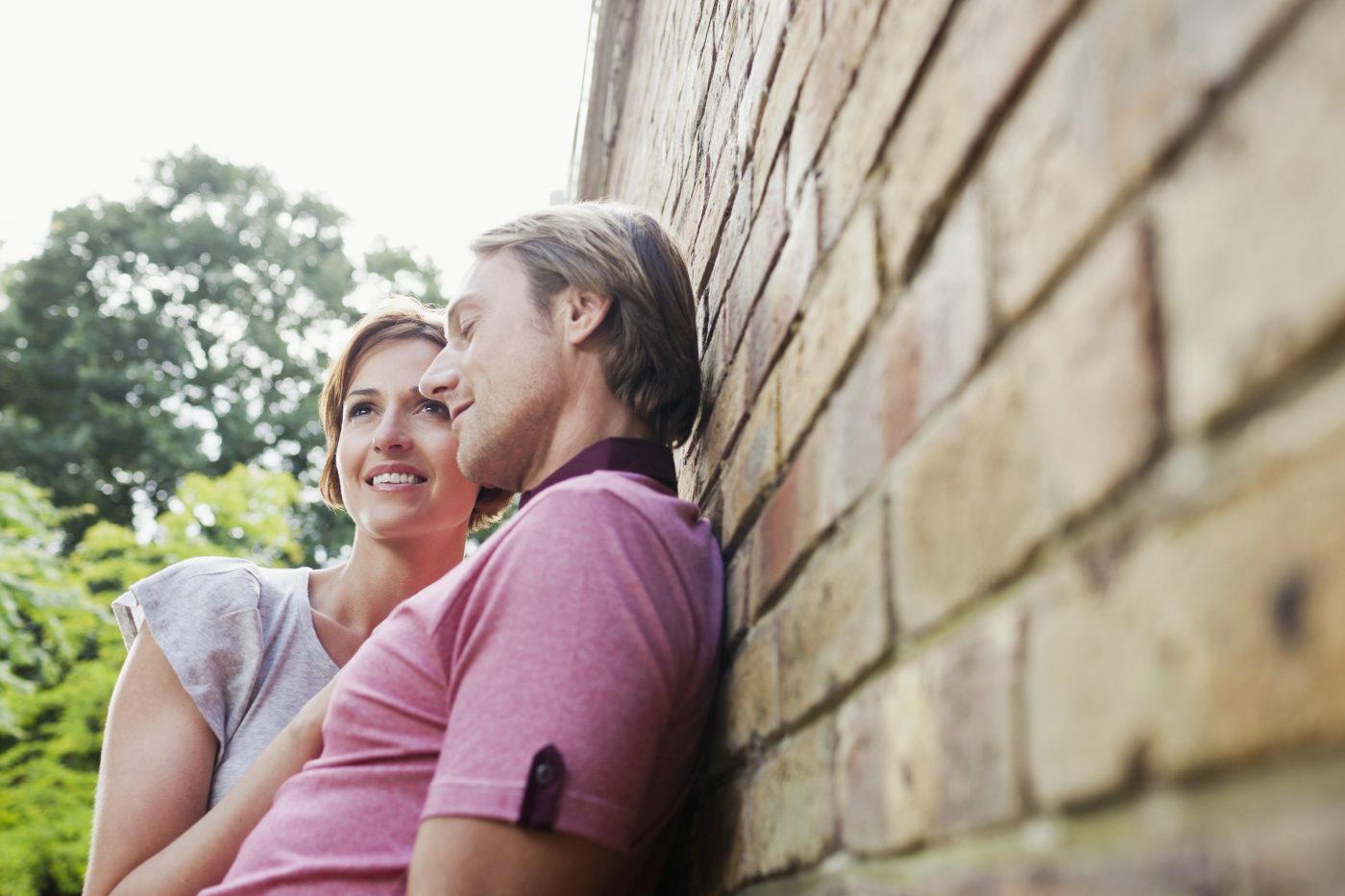 Young loving couple leaning against brick façade